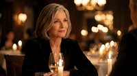 Elegant mature blonde woman enjoying candlelit dinner in upscale restaurant with warm ambient lighting and sophisticated atmosphere for dining concepts.