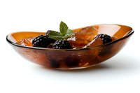 Fresh blackberries and mint leaf garnish in amber glass bowl with white background, elegant food styling for restaurant menu and culinary presentations.