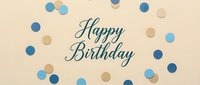 Happy Birthday script lettering on beige background with blue and gold confetti dots scattered around, festive flat lay celebration card design.
