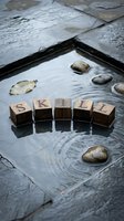 Wooden letter blocks spelling skill arranged in shallow water with smooth stones and ripples, zen garden meditation concept for personal development and mindfulness training.
