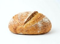 Freshly baked artisan sourdough loaf with crispy golden crust and flour dusting, isolated on white background for bakery, food, and culinary design use.