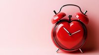 Red heart-shaped alarm clock on pink background symbolizing love timing, romance deadlines, Valentine's Day concepts for relationship themes.