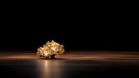 Crumpled gold foil ball on dark wooden surface with dramatic lighting and reflection creates luxurious minimalist composition for advertising and design projects.