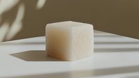 Single white sugar cube casting soft shadow on light surface in minimalist composition with natural lighting and neutral beige background.
