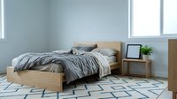 Modern minimalist bedroom interior with wooden bed frame, gray bedding, geometric rug and natural light from large windows for home decor inspiration.
