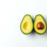 Fresh ripe avocado halves with pit on clean white background for healthy cooking and nutrition content.