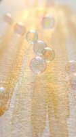 Floating soap bubbles with rainbow reflections against warm golden sunlight background creating dreamy atmospheric effect for relaxation and wellness concepts.