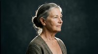 Senior Caucasian woman with gray hair in profile view against dark background, contemplative expression, natural aging, mature lifestyle portrait.