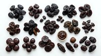 Dried raisins and prunes arranged in groups on white background, showing various sizes and dark brown colors for food styling, nutrition content, and culinary use.