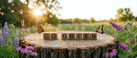 Wooden letter blocks spelling GO GREEN on tree stump surrounded by purple wildflowers and butterflies at golden hour sunset promoting eco-friendly lifestyle.
