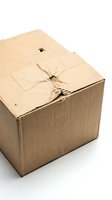 Damaged brown cardboard shipping box with torn tape and dents isolated on white background for packaging and delivery concepts.