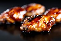 Glazed barbecue chicken drumsticks with caramelized sauce on dark background. Grilled poultry with sticky sweet coating for restaurant menu and cooking content.