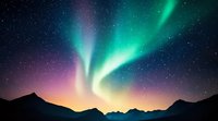 Northern lights dance across starry night sky over mountain silhouettes, featuring vibrant green aurora borealis and purple-pink horizon glow in dramatic natural light show.