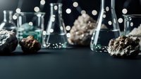 Laboratory glassware with mineral specimens and rock samples for geological research and scientific analysis in modern chemistry lab setting.