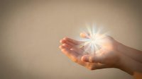 Hand holding glowing light burst, symbolizing hope, spirituality, healing energy, and divine blessing for wellness and inspirational concepts.