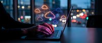 Businessman using laptop with glowing cloud computing icons in modern office at night for data storage and digital transformation solutions.