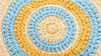 Handmade crochet mandala in soft yellow and blue colors with concentric circles pattern for home decor and craft projects.