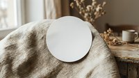 Empty white ceramic plate on natural linen fabric with dried flowers and wooden table creating warm minimalist kitchen styling for food photography.