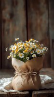 Bouquet of white and yellow daisies wrapped in kraft paper with twine bow, arranged on rustic wooden surface with weathered background, suitable for greeting cards and home decor.