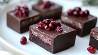 Dark chocolate squares filled with cranberry mousse and topped with fresh cranberries on white surface, elegant dessert presentation for gourmet confectionery.