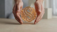 Person with medium skin tone holding golden spherical object with swirl pattern, suitable for business, finance, wealth, and success concepts.