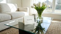 Elegant living room with white tulips in a glass vase and a thank you card on a coffee table, bright and cozy home interior.