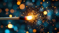 Burning match with bright sparks and golden bokeh lights against dark blue background creates magical atmosphere. Perfect for festive designs.