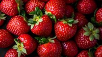 Fresh ripe strawberries with green leaves close up macro shot. Bright red berries background showing natural texture and juicy details in dark setting.