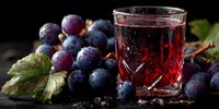 Fresh dark grapes with crystal glass of red grape juice on rustic wooden table. Healthy organic fruit beverage for breakfast or snack time.