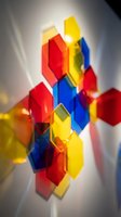 Stacked translucent colored glass cubes in red, yellow, and blue creating an abstract geometric composition with light refraction and glowing effects.