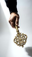 Male hand holding ornate golden vintage key with decorative baroque design against white background for business success and opportunity concepts.