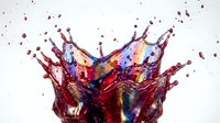 Dynamic red wine splash with colorful light reflections creating crown-like formation against white background for beverage advertising and culinary design.