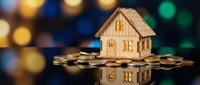 Wooden house model sitting on pile of coins with colorful bokeh lights background representing real estate investment and property financing concepts.