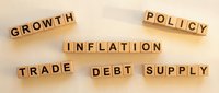 Wooden letter blocks spelling economic terms including growth, policy, inflation, trade, debt and supply arranged on neutral background for business concepts.