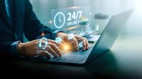 Professional businessman using laptop with glowing 24/7 online support interface icons for customer service and technical assistance solutions.