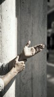 Male hands reaching out from concrete pillar in urban environment expressing help, support or connection in architectural setting.
