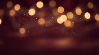Warm golden bokeh lights creating magical atmosphere on dark burgundy background with sparkling particles for festive celebrations and luxury events.