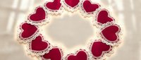 Red heart-shaped cookies arranged in circle on white surface with flour dusting creating romantic Valentine's Day dessert display for bakery menu design.