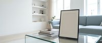 Modern minimalist living room interior with glass coffee table, gray sofa, white shelving and natural light for home decor and design projects.