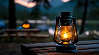 Vintage oil lantern with warm glowing light on wooden surface at dusk, creating atmospheric outdoor ambiance with blurred pumpkin decoration in background.