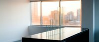 Modern minimalist office conference room with sleek black table and glass panels overlooking urban cityscape at sunset for corporate business meetings.