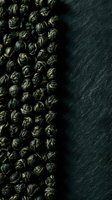 Dried green tea leaves arranged in a line on dark slate surface, showcasing organic tea production and beverage ingredients for culinary and wellness design projects.