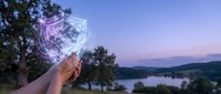 Hand holding glowing holographic cube with digital network connections against twilight lake landscape for technology and innovation concepts.