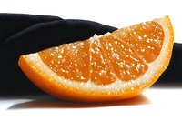 Fresh juicy orange segment with visible pulp and natural texture on black and white background, macro photography showing detailed citrus flesh structure.