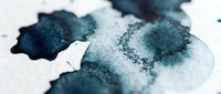 Macro shot of teal and navy watercolor paint splatters with crystalline salt texture on white paper, suitable for artistic backgrounds and design projects.