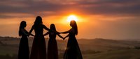 Four women holding hands in silhouette against golden sunset sky, symbolizing friendship, unity and sisterhood in peaceful outdoor landscape setting.