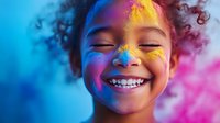 Young African American girl with curly hair laughing joyfully while colorful holi powder paint creates vibrant blue, pink and yellow patterns on her face against multicolored background.