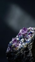 Raw amethyst crystal cluster with purple gemstones and metallic minerals on dark background for geology education and mineral collection displays.