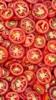 Fresh sliced red tomatoes arranged in rows showing inner seed structure and flesh, creating natural pattern background for food industry and healthy eating concepts.