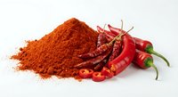 Red chili pepper powder pile with fresh hot peppers isolated on white background for cooking spice seasoning culinary ingredient kitchen design.